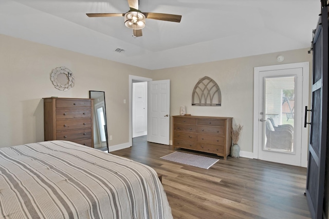 bedroom with a barn door, wood finished floors, visible vents, baseboards, and access to outside