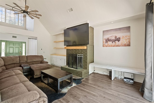living room featuring visible vents, a ceiling fan, wood finished floors, a fireplace, and high vaulted ceiling