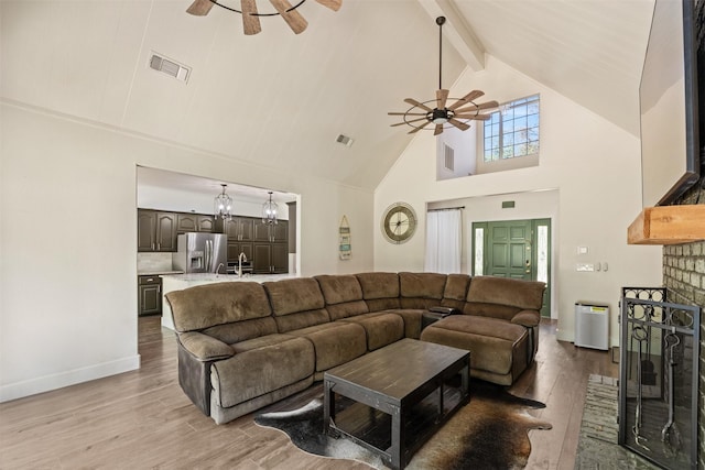 living area featuring visible vents, light wood-style floors, beamed ceiling, a ceiling fan, and high vaulted ceiling
