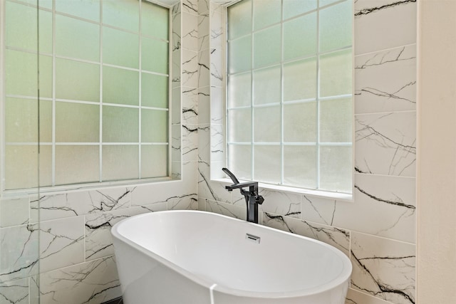full bath with tile walls and a soaking tub