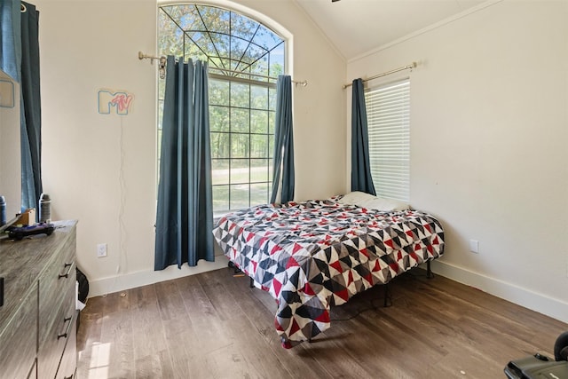 bedroom with lofted ceiling, ornamental molding, baseboards, and wood finished floors