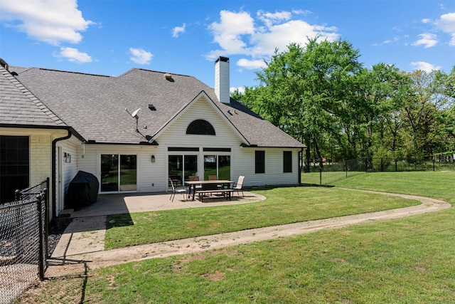 back of property featuring fence, a yard, a patio, and a shingled roof