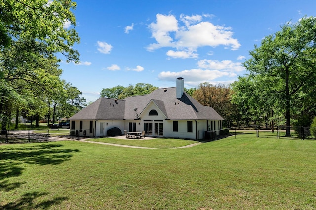 back of house with a fenced backyard, a chimney, a patio area, a lawn, and a shingled roof