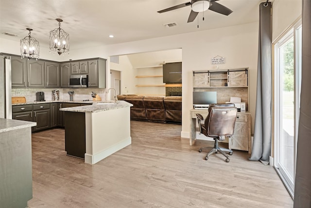 kitchen with stainless steel microwave, visible vents, decorative backsplash, and ceiling fan with notable chandelier