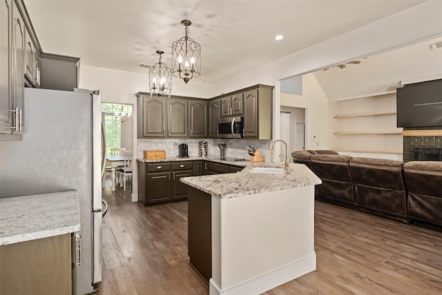kitchen with a peninsula, a sink, dark wood-style flooring, open floor plan, and appliances with stainless steel finishes