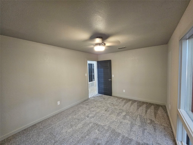 unfurnished bedroom with carpet flooring, a textured ceiling, visible vents, baseboards, and ceiling fan