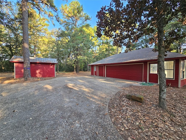 view of side of property featuring a detached garage, an outbuilding, a shed, and driveway