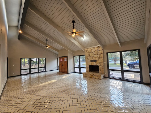 unfurnished living room with high vaulted ceiling, ceiling fan, beamed ceiling, a fireplace, and baseboards
