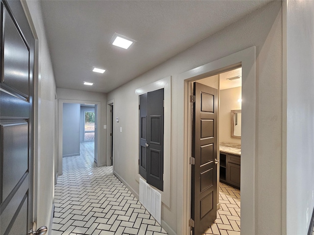 hallway featuring baseboards, brick floor, and visible vents