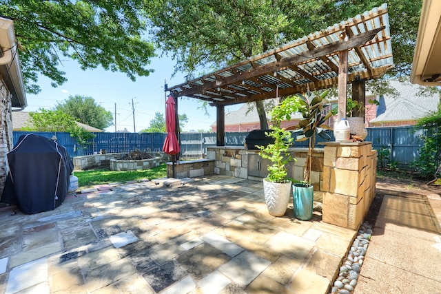 view of patio featuring a fenced backyard, a pergola, area for grilling, and an outdoor kitchen