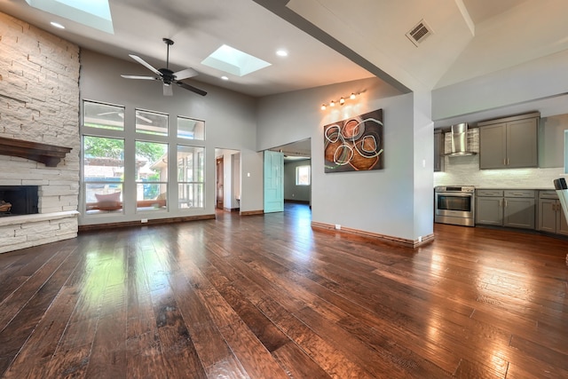 unfurnished living room with visible vents, high vaulted ceiling, dark wood-style floors, and a skylight