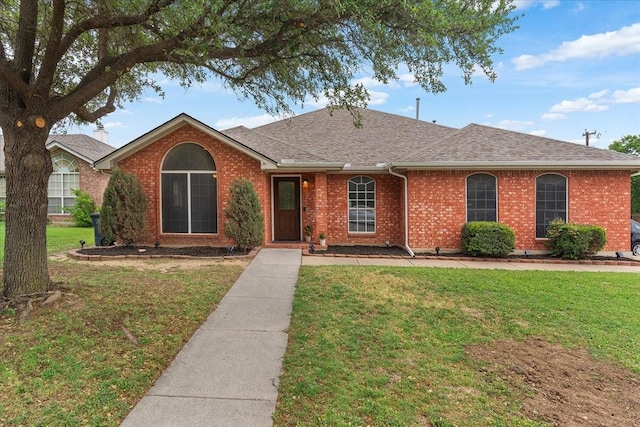 ranch-style home with brick siding, roof with shingles, and a front yard