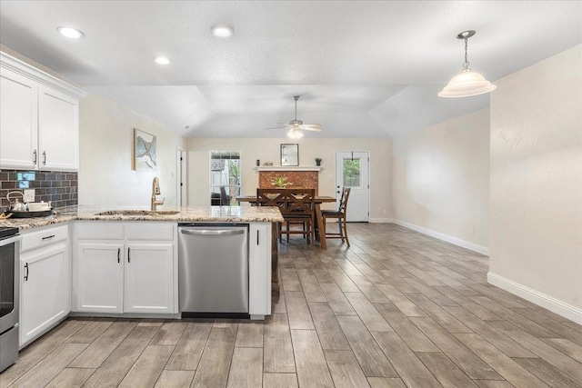 kitchen featuring stainless steel appliances, a sink, light wood-type flooring, a peninsula, and ceiling fan