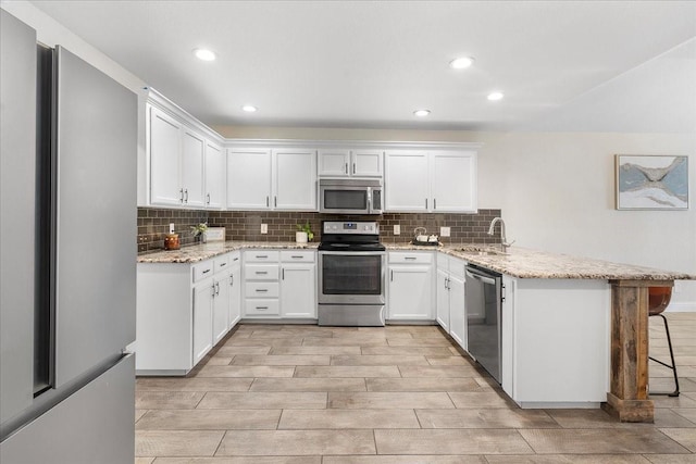 kitchen featuring a peninsula, tasteful backsplash, stainless steel appliances, and a sink