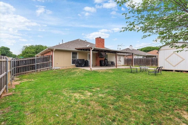rear view of house featuring a chimney, a fenced backyard, a yard, a patio, and a storage unit