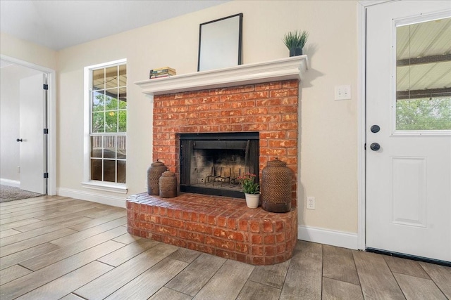 living room with wood finished floors, a brick fireplace, and baseboards