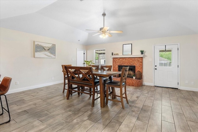 dining area featuring lofted ceiling, light wood-style flooring, a brick fireplace, and a wealth of natural light