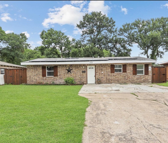 7025 Atha Dr, Dallas, TX 75217 - ranch-style home featuring a front lawn, brick siding, fence, and roof mounted solar panels