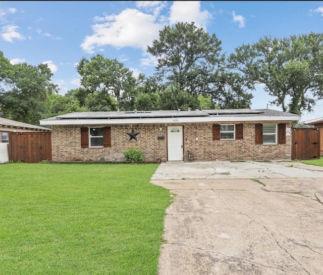 7025 Atha Dr, Dallas, TX 75217 - ranch-style home featuring a front lawn, brick siding, fence, and roof mounted solar panels