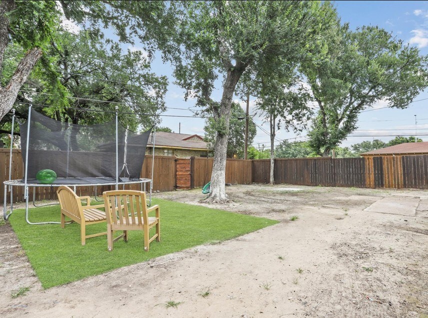 7025 Atha Dr, Dallas, TX 75217 - view of yard featuring a fenced backyard and a trampoline