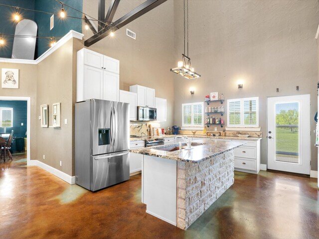 kitchen with concrete floors, appliances with stainless steel finishes, a towering ceiling, and a sink