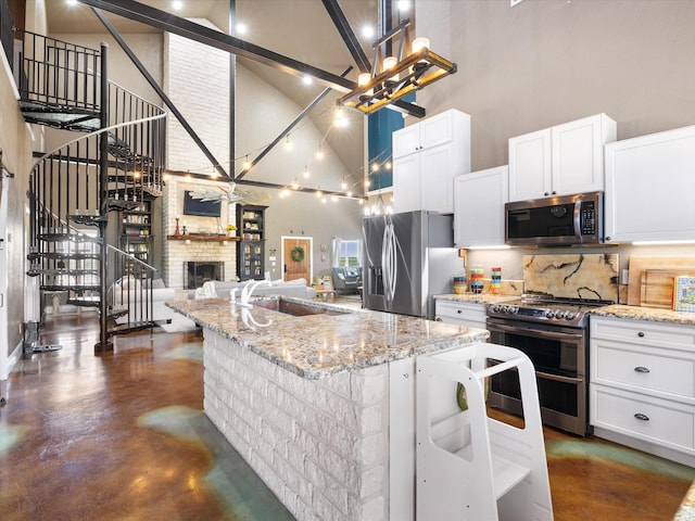 kitchen with stainless steel appliances, a center island with sink, tasteful backsplash, white cabinetry, and high vaulted ceiling
