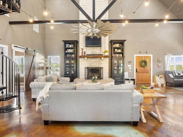 living area featuring a towering ceiling, finished concrete flooring, ceiling fan, and a barn door