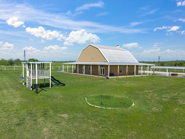 back of property featuring a gambrel roof, a chimney, a playground, a lawn, and metal roof