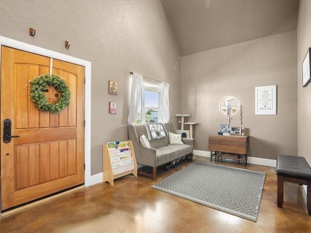 sitting room with concrete floors, lofted ceiling, and baseboards