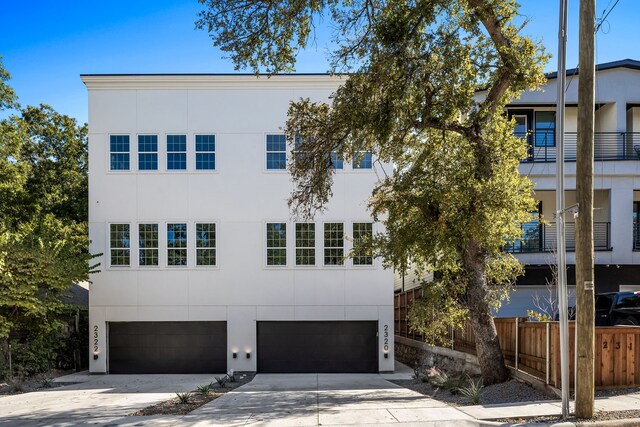 2322 Arroyo Ave, Dallas, TX 75219 - view of property featuring stucco siding, concrete driveway, an attached garage, and fence