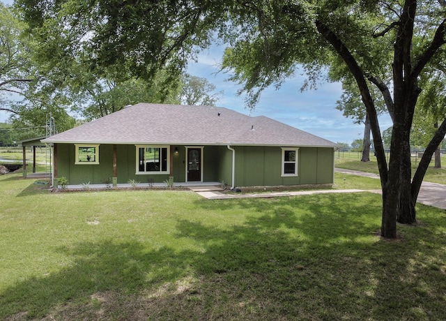 rear view of house featuring a yard, a shingled roof, and covered porch