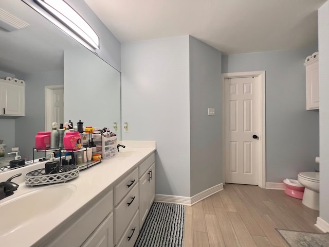 2631 Lillian St, Shreveport, LA 71103 - bathroom featuring a sink, double vanity, toilet, baseboards, and wood finished floors