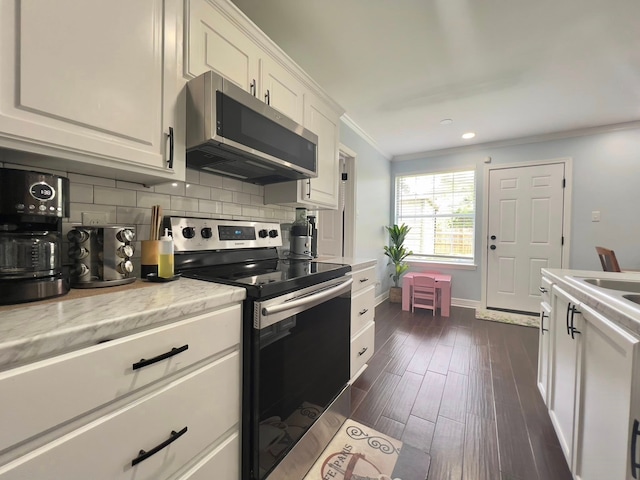 2631 Lillian St, Shreveport, LA 71103 - kitchen with white cabinets, dark wood-style floors, backsplash, ornamental molding, and appliances with stainless steel finishes