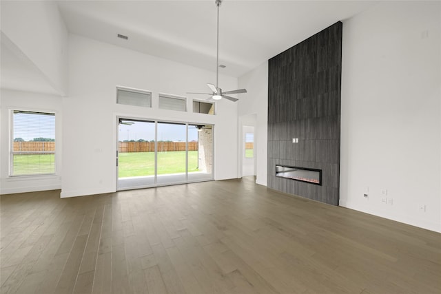 431 Broadmoor, Ovilla, TX 75154 - unfurnished living room featuring wood finished floors, a towering ceiling, a ceiling fan, a fireplace, and baseboards