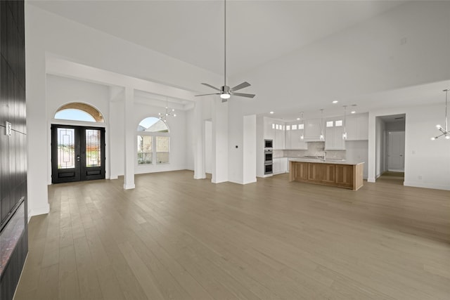431 Broadmoor, Ovilla, TX 75154 - unfurnished living room with a chandelier, light wood finished floors, baseboards, a ceiling fan, and french doors