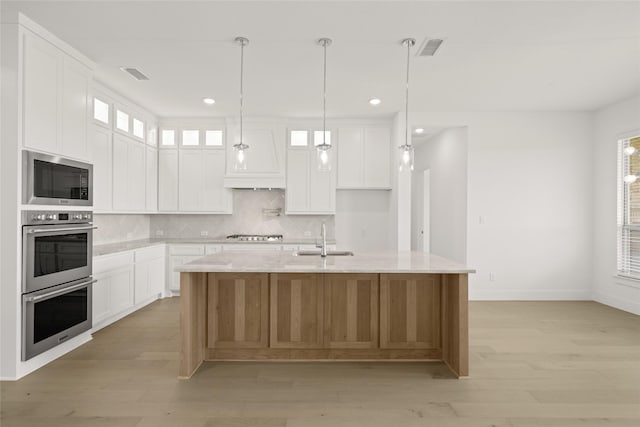 431 Broadmoor, Ovilla, TX 75154 - kitchen featuring stainless steel appliances, a sink, backsplash, light wood finished floors, and an island with sink