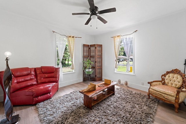 living area with baseboards, wood finished floors, and ceiling fan