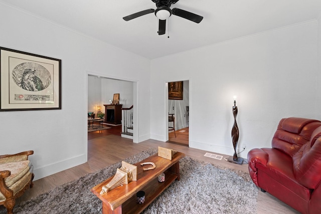 living room with a ceiling fan, ornamental molding, wood finished floors, and visible vents