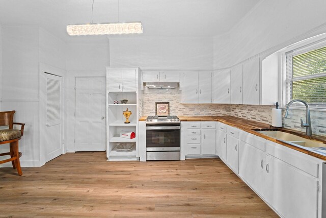 kitchen featuring a sink, tasteful backsplash, white cabinetry, stainless steel gas stove, and under cabinet range hood