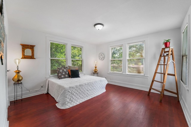 bedroom with baseboards, wood finished floors, and multiple windows