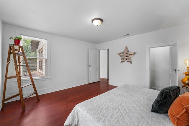 bedroom featuring baseboards, wood finished floors, and visible vents