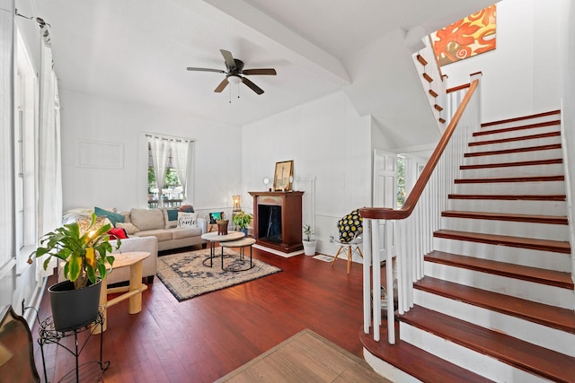 living room with a multi sided fireplace, wood finished floors, stairs, and ceiling fan