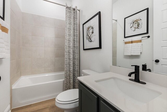 full bath with wood finished floors, shower / tub combo, toilet, and vanity