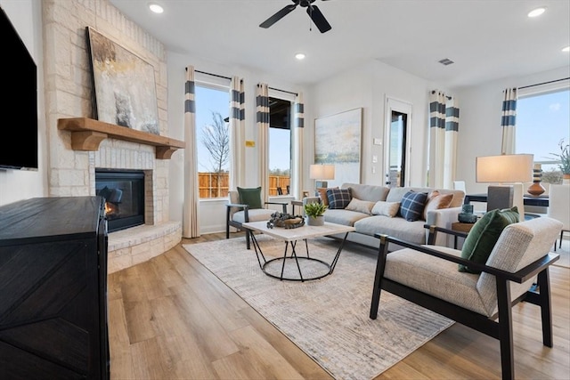 living area with a stone fireplace, a ceiling fan, wood finished floors, and recessed lighting