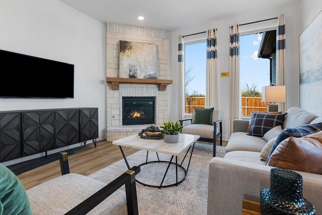 living area featuring baseboards, recessed lighting, wood finished floors, and a fireplace