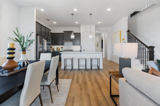 dining space featuring recessed lighting, light wood-style floors, and stairs