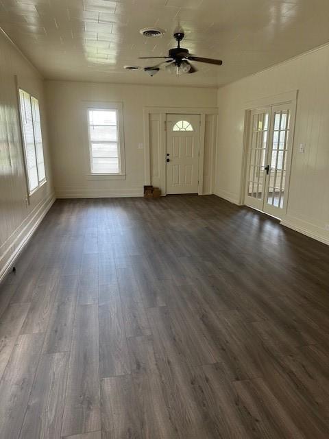 unfurnished living room featuring dark wood finished floors, ceiling fan, visible vents, and plenty of natural light