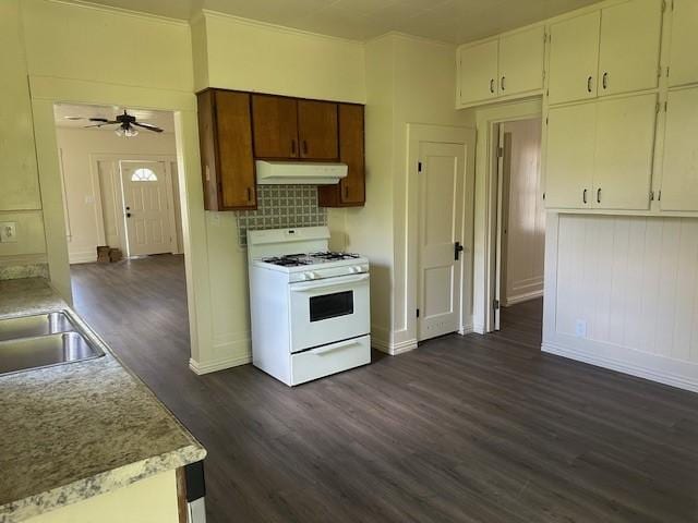 kitchen with white gas range oven, dark wood-style floors, a ceiling fan, light countertops, and under cabinet range hood