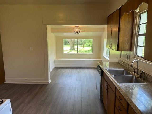 kitchen featuring a notable chandelier, brown cabinetry, a sink, and dark wood-type flooring