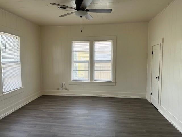 empty room featuring dark wood-type flooring, a ceiling fan, and baseboards